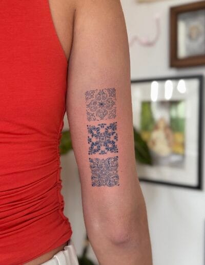 Small azulejo tattoo set on forearm with three Portuguese tile patterns, fine line tattoo in Porto