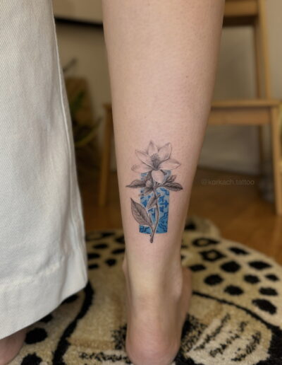 Fine line botanical flower tattoo on calf with blue azulejo tile detail, Porto tattoo