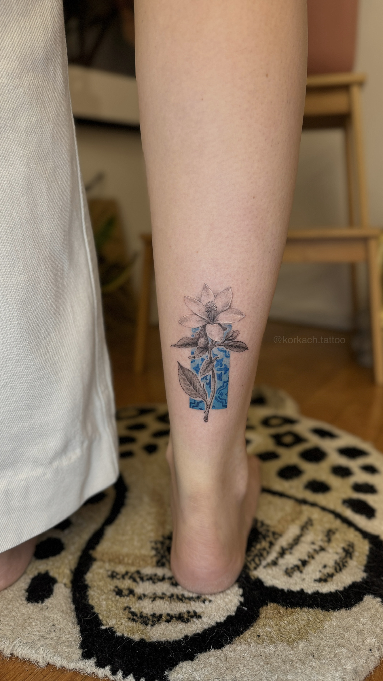 Fine line botanical flower tattoo on calf with blue azulejo tile detail, Porto tattoo