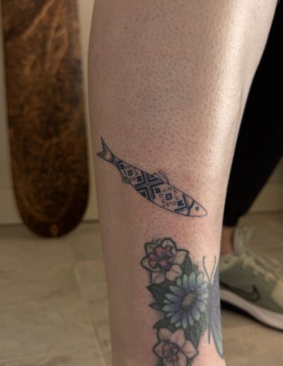 Fine line sardine tattoo on calf with azulejo tile pattern, small Portuguese tattoo Porto