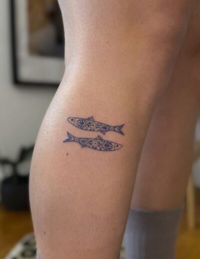 Minimalist sardine tattoo on leg with blue azulejo tile pattern, small Portuguese tattoo Porto