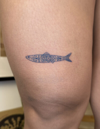 Minimalist sardine tattoo on hip with blue azulejo tile pattern, small Portuguese tattoo Porto