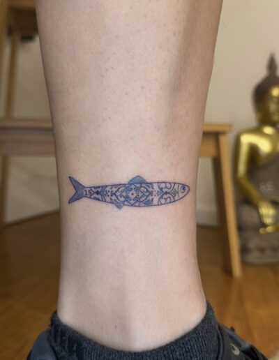 Minimalist sardine tattoo on lower leg with blue azulejo tile pattern, Portuguese tattoo Porto
