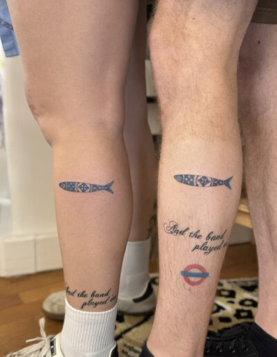 Matching sardine tattoos on legs with blue azulejo tile pattern, minimalist couple tattoo Porto