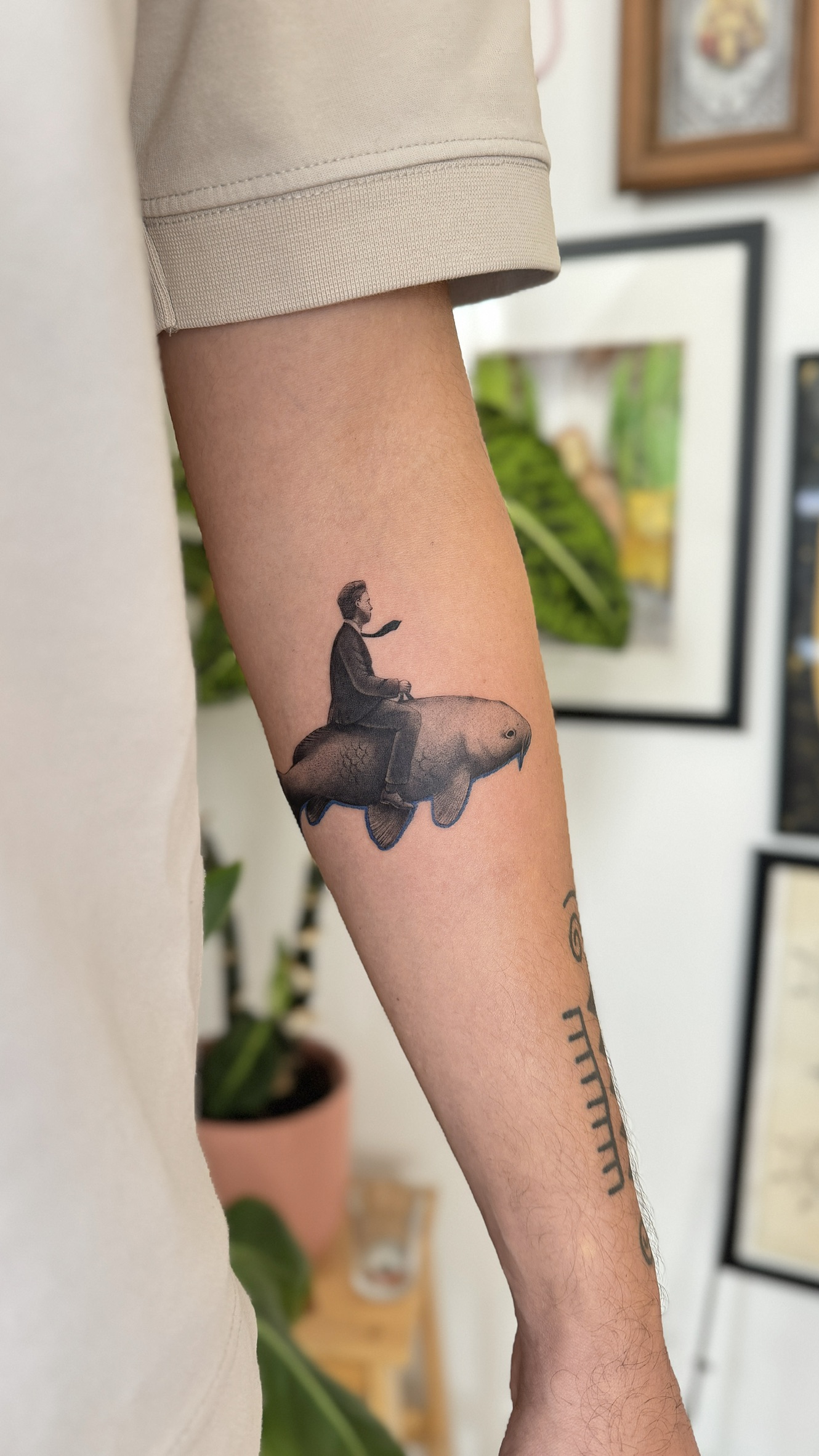 Surreal tattoo of man sitting on fish, micro realism style on arm in Porto Portugal by KORKACH Kateryna