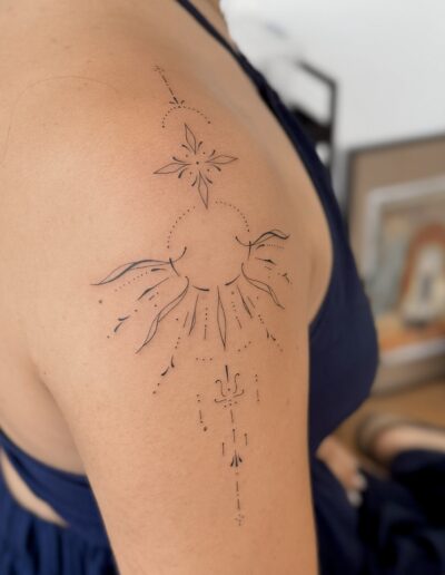 Fine line ornamental sun and star tattoo on shoulder in Porto Portugal by KORKACH Kateryna