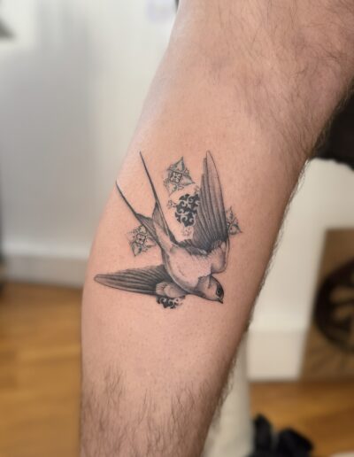 Fine line swallow bird tattoo on arm in Porto Portugal by KORKACH Kateryna with soft shading and azulejo elements