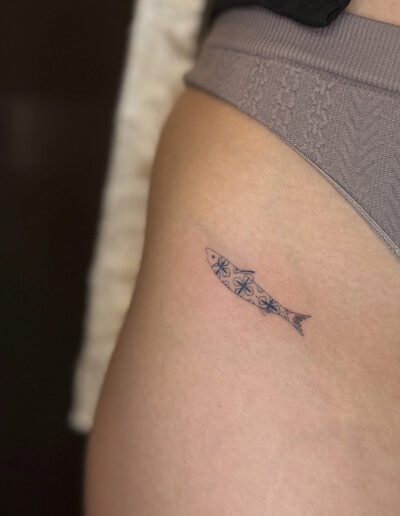Fine line sardine tattoo with azulejo pattern on hip in Porto Portugal by KORKACH Kateryna